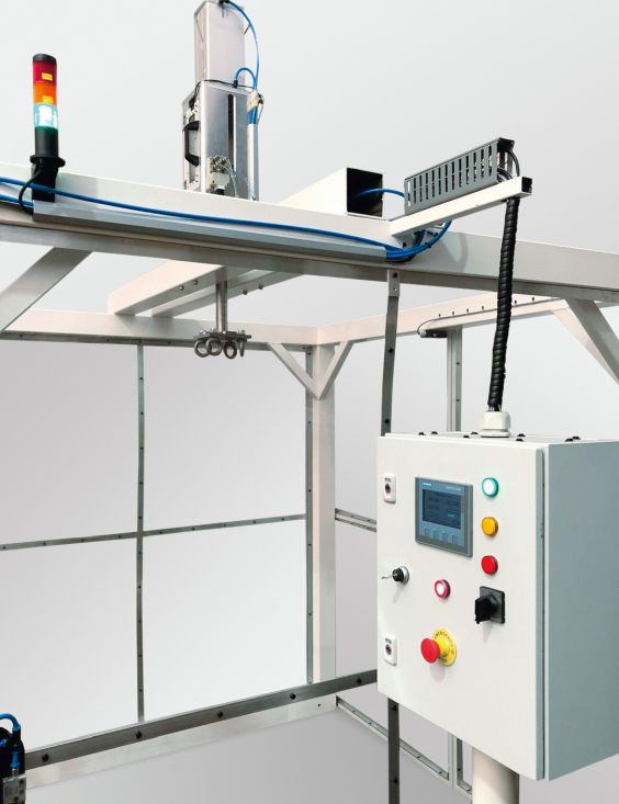 Drop test unit for testing the stability of wheelchairs with controls in the foreground on the right and the pneumatically operated construction for engaging and disengaging the wheelchairs at the top